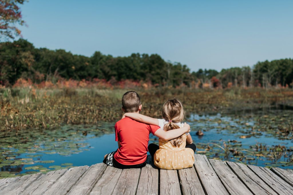 due bambini seduti in riva a un laghetto