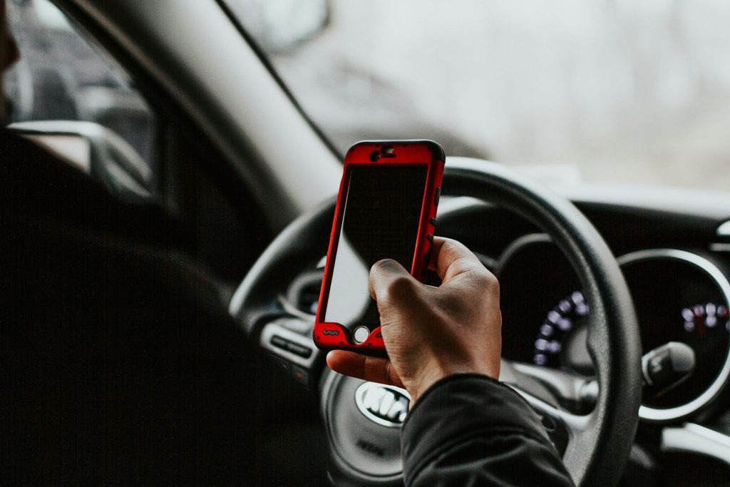 Persona al volante con cellulare rosso